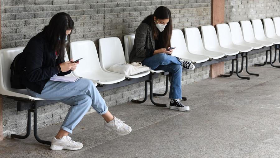 Dúas estudantes consultan os seus móbiles nun espazo universitario