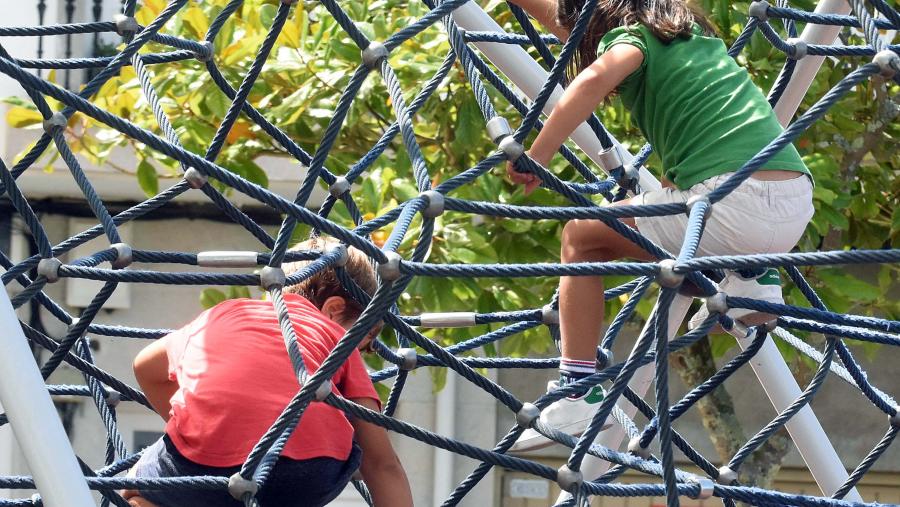Nenos e nenas xogando nun parque infantil